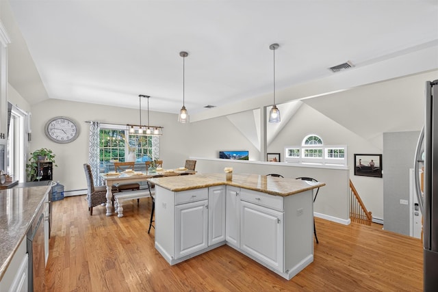 311 Myers Corners Rd, Wappingers Falls, NY 12590 - kitchen with vaulted ceiling, light wood-type flooring, white cabinets, a breakfast bar area, and hanging light fixtures