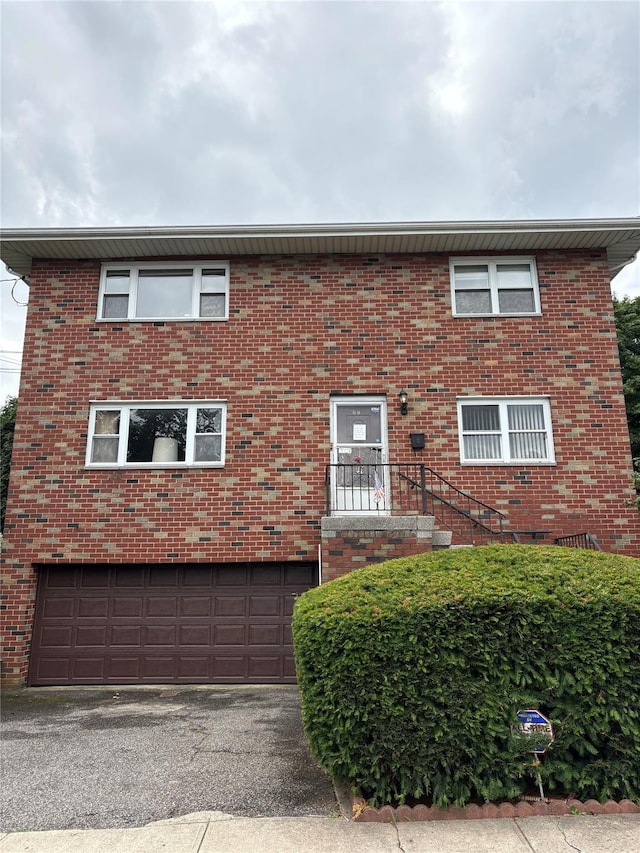 68 Loring Ave, Yonkers, NY 10704 - view of front of home with an attached garage, asphalt driveway, and brick siding