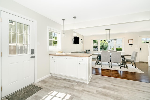 14 Crocus Ct, West Babylon, NY 11704 - kitchen featuring light wood finished floors, plenty of natural light, white cabinetry, and pendant lighting