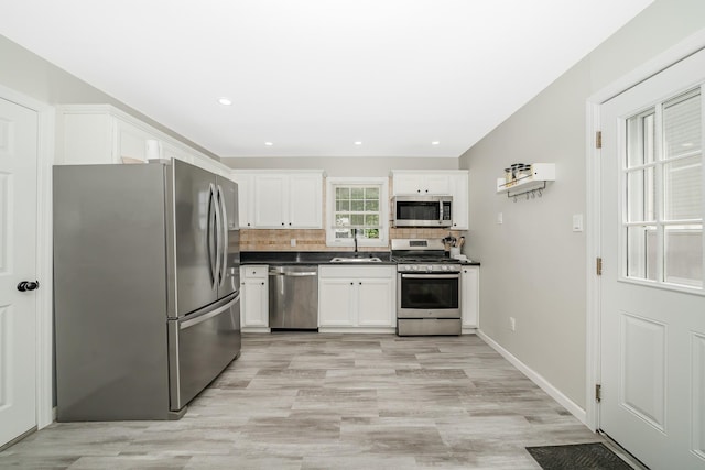 14 Crocus Ct, West Babylon, NY 11704 - kitchen featuring stainless steel appliances, dark countertops, white cabinetry, tasteful backsplash, and light wood-style flooring