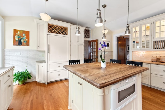 28 Shore Rd, Douglaston, NY 11363 - kitchen with lofted ceiling, white cabinetry, decorative backsplash, and decorative light fixtures