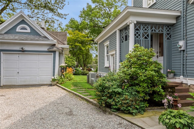 28 Shore Rd, Douglaston, NY 11363 - view of side of property featuring gravel driveway, a garage, and a shingled roof