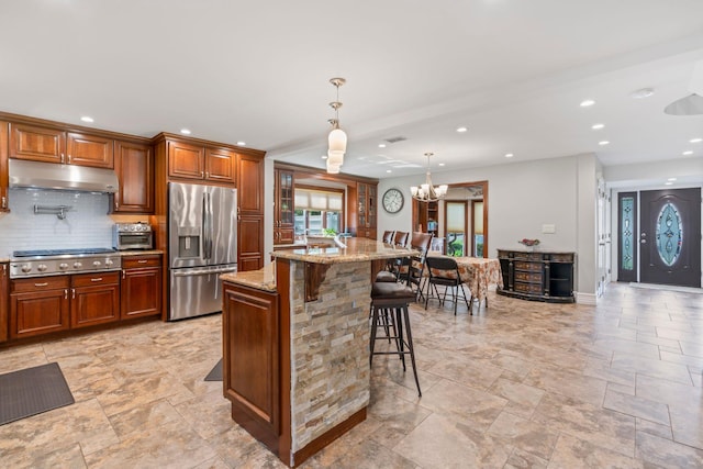 20 Tulipwood Dr, Commack, NY 11725 - kitchen with stainless steel appliances, under cabinet range hood, stone tile flooring, a kitchen breakfast bar, and decorative backsplash