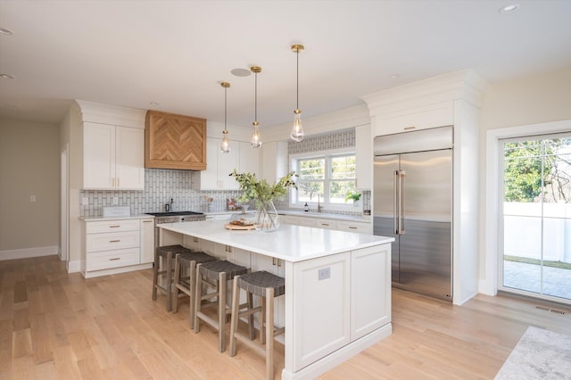 1585A Dewey Ave, North Bellmore, NY 11710 - kitchen with built in fridge, custom range hood, white cabinetry, and light wood finished floors