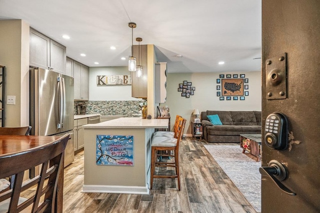 42 Richmond Blvd Unit 3B, Ronkonkoma, NY 11779 - kitchen with stainless steel appliances, wood finished floors, a breakfast bar, decorative backsplash, and a peninsula