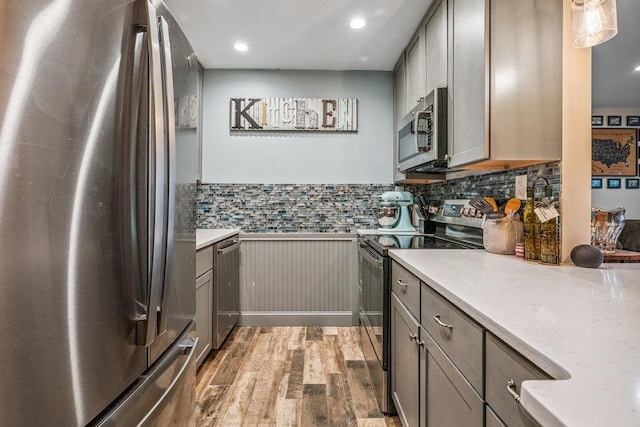 42 Richmond Blvd Unit 3B, Ronkonkoma, NY 11779 - kitchen featuring appliances with stainless steel finishes, wood finished floors, gray cabinets, a wainscoted wall, and backsplash