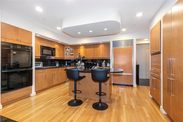 1 Portico Ct Unit 200, Great Neck, NY 11021 - kitchen featuring black appliances, light wood-style flooring, brown cabinets, a breakfast bar area, and recessed lighting