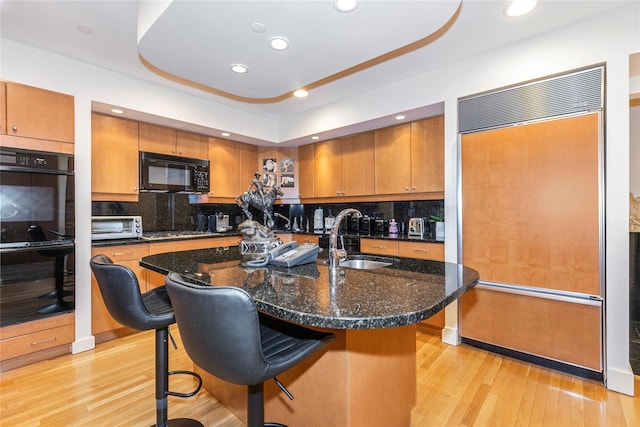 1 Portico Ct Unit 200, Great Neck, NY 11021 - kitchen with black appliances, brown cabinetry, light wood-style flooring, a kitchen bar, and recessed lighting