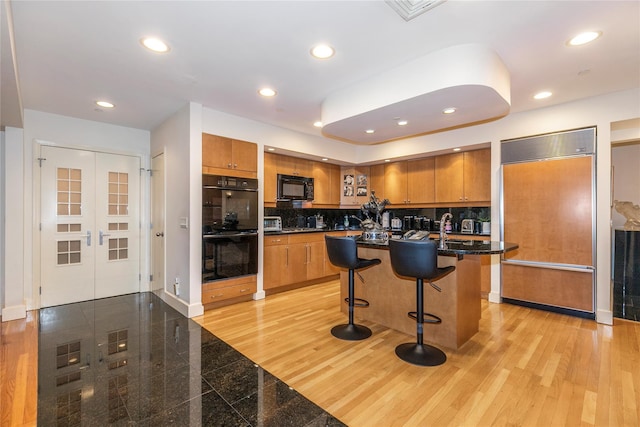 1 Portico Ct Unit 200, Great Neck, NY 11021 - kitchen featuring black appliances, brown cabinets, a breakfast bar, decorative backsplash, and recessed lighting
