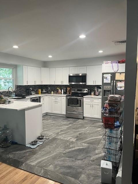 226 14th Ave, West Babylon, NY 11704 - kitchen with appliances with stainless steel finishes, white cabinets, tasteful backsplash, light countertops, and recessed lighting
