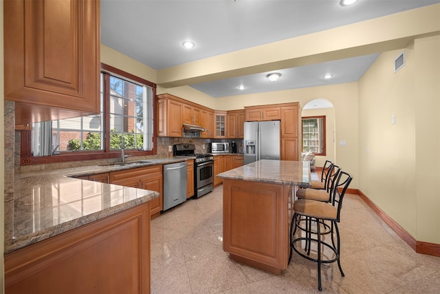 83-14 266th St, Glen Oaks, NY 11004 - kitchen featuring appliances with stainless steel finishes, light stone counters, a breakfast bar, plenty of natural light, and recessed lighting