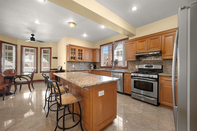 83-14 266th St, Glen Oaks, NY 11004 - kitchen with appliances with stainless steel finishes, under cabinet range hood, granite floors, a kitchen breakfast bar, and recessed lighting