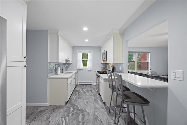 1690 Grand Ave Unit A16, Baldwin, NY 11510 - kitchen featuring stainless steel appliances, a baseboard radiator, light countertops, tasteful backsplash, and recessed lighting