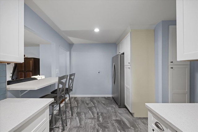 1690 Grand Ave Unit A16, Baldwin, NY 11510 - kitchen featuring freestanding refrigerator, white cabinets, light countertops, a breakfast bar, and recessed lighting