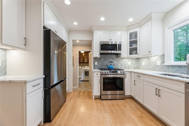 43 Woodglen Dr, New City, NY 10956 - kitchen featuring appliances with stainless steel finishes, washer and dryer, white cabinets, light wood finished floors, and tasteful backsplash