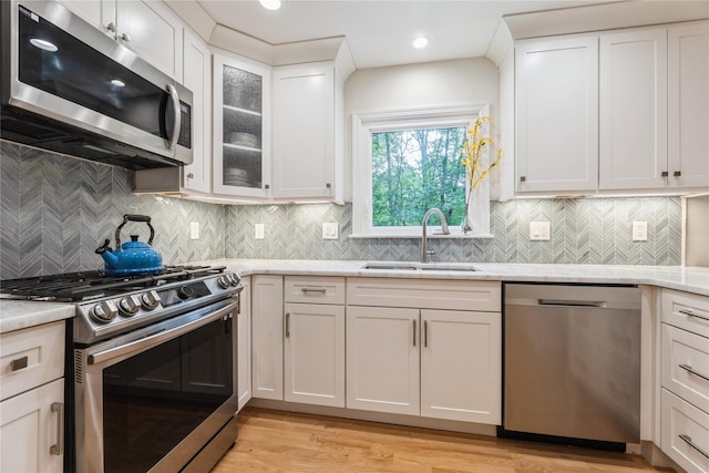 43 Woodglen Dr, New City, NY 10956 - kitchen with stainless steel appliances, white cabinets, light wood-style floors, light stone counters, and glass insert cabinets