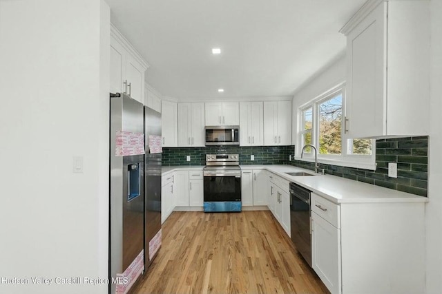 1601 Rte 199, Red Hook, NY 12571 - kitchen with stainless steel appliances, light wood-type flooring, decorative backsplash, white cabinetry, and light countertops