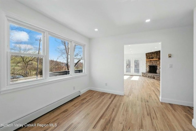 1601 Rte 199, Red Hook, NY 12571 - unfurnished room with a baseboard radiator, light wood finished floors, a stone fireplace, french doors, and recessed lighting