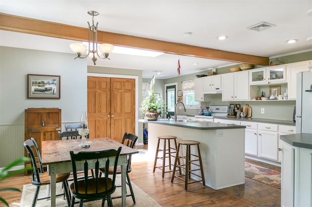 7 Clover Ln, Brookhaven, NY 11719 - kitchen with white appliances, under cabinet range hood, a center island with sink, white cabinetry, and dark countertops
