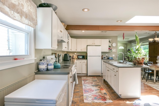 7 Clover Ln, Brookhaven, NY 11719 - kitchen featuring white appliances, white cabinets, under cabinet range hood, a kitchen island with sink, and dark countertops