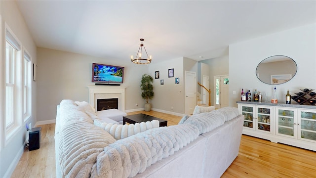 9 Shaw Ln, East Moriches, NY 11940 - living room with a chandelier, a fireplace, light wood-style floors, and healthy amount of natural light