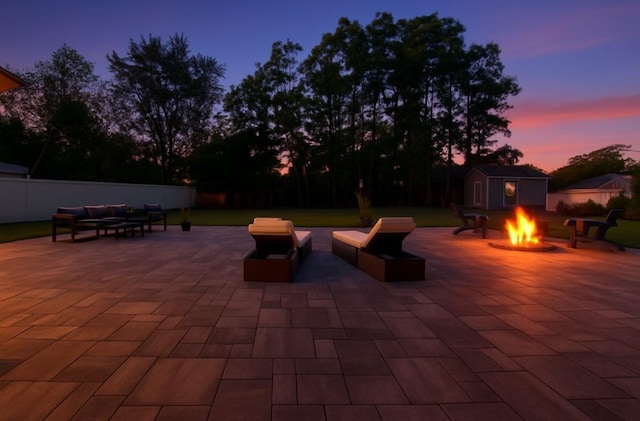 9 Shaw Ln, East Moriches, NY 11940 - patio terrace at dusk featuring an outdoor living space with a fire pit, a patio area, an outdoor structure, and a fenced backyard
