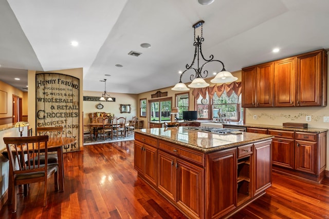 24 Croft Ln, Smithtown, NY 11787 - kitchen with dark wood finished floors, light stone countertops, stainless steel gas stovetop, a kitchen island, and hanging light fixtures