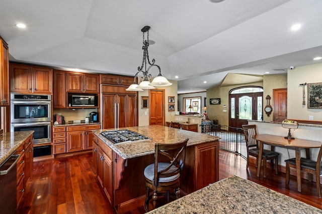 24 Croft Ln, Smithtown, NY 11787 - kitchen featuring appliances with stainless steel finishes, dark wood-style flooring, a breakfast bar, light stone counters, and a kitchen island