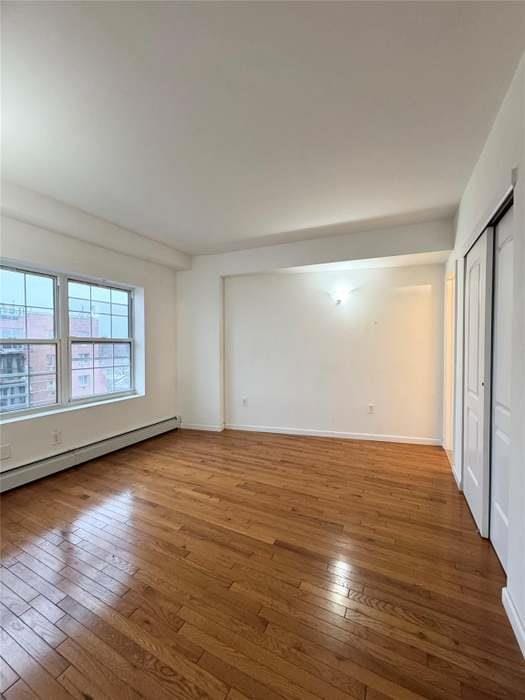 7166 Parsons Blvd Unit 6E, Fresh Meadows, NY 11365 - empty room with a baseboard radiator and wood-type flooring