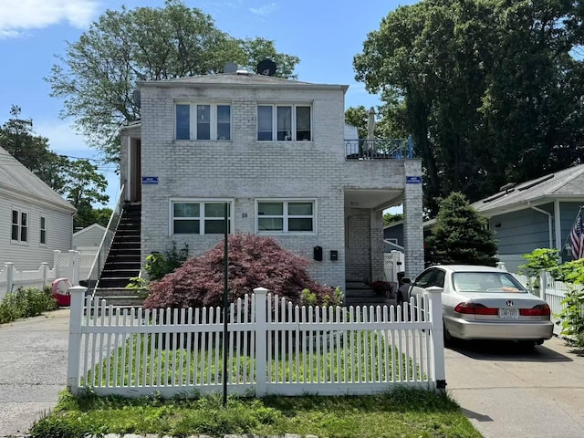 38 Nesaquake Ave, Port Washington, NY 11050 - view of front of house with stairway, brick siding, a fenced front yard, and concrete driveway