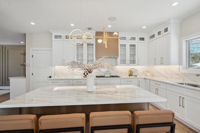 11 Vernon St, Plainview, NY 11803 - kitchen with gas stovetop, white cabinets, decorative backsplash, a kitchen breakfast bar, and recessed lighting