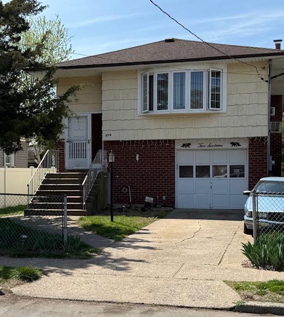216 Hill Ave, Elmont, NY 11003 - view of front of home with brick siding, an attached garage, and concrete driveway
