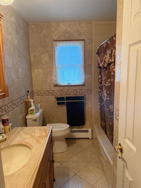 216 Hill Ave, Elmont, NY 11003 - full bath with baseboard heating, tile patterned floors, tile walls, vanity, and shower / bath combination with curtain