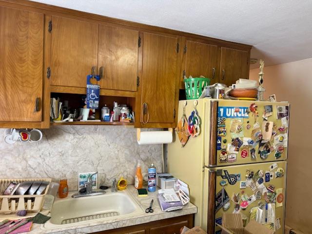 216 Hill Ave, Elmont, NY 11003 - kitchen with freestanding refrigerator, light countertops, backsplash, and brown cabinetry