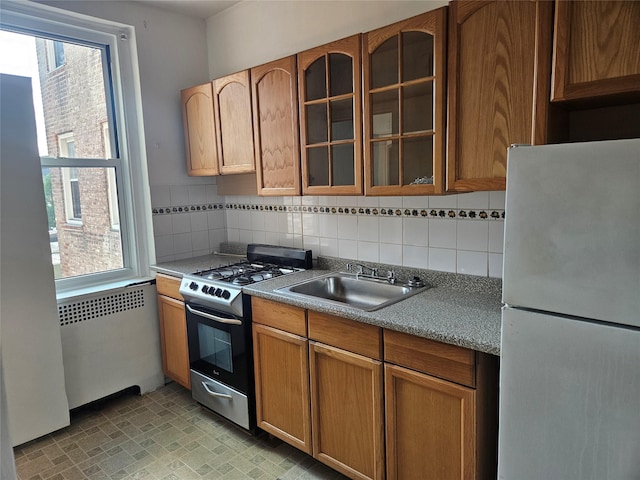 7215 37th Ave Unit 3H, Jackson Heights, NY 11372 - kitchen with freestanding refrigerator, gas range, radiator, glass insert cabinets, and backsplash