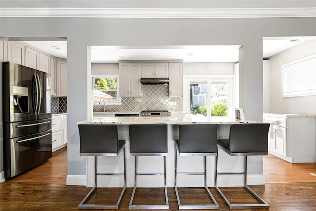 3 Grant Ave, Albertson, NY 11507 - kitchen featuring stainless steel fridge, under cabinet range hood, tasteful backsplash, dark wood-style flooring, and ornamental molding
