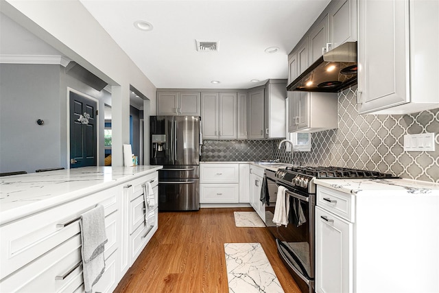 3 Grant Ave, Albertson, NY 11507 - kitchen with gas range oven, fridge with ice dispenser, under cabinet range hood, gray cabinets, and wood finished floors