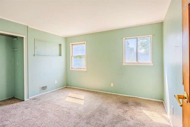 12 Rivera Ln, West Sayville, NY 11796 - unfurnished bedroom featuring multiple windows, carpet flooring, ornamental molding, wooden walls, and a closet