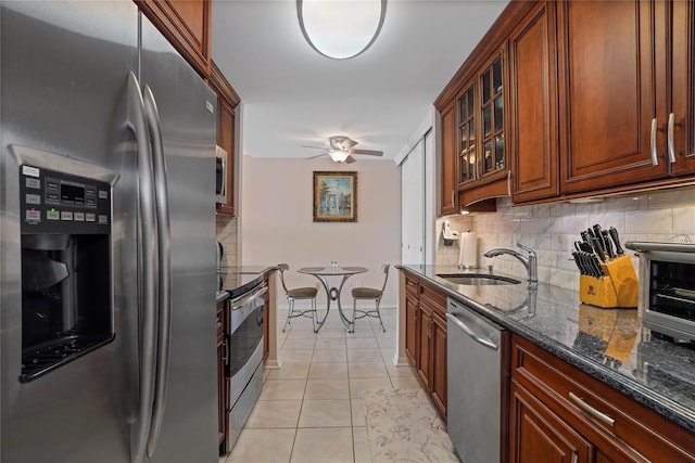 100 High Point Dr Unit 310, Hartsdale, NY 10530 - kitchen featuring appliances with stainless steel finishes, decorative backsplash, dark stone countertops, a ceiling fan, and glass insert cabinets