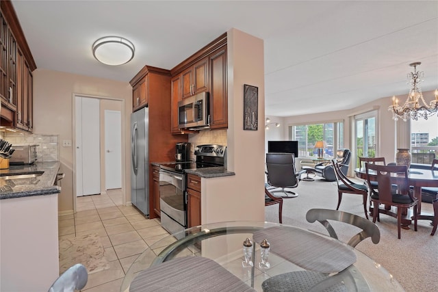 100 High Point Dr Unit 310, Hartsdale, NY 10530 - kitchen featuring stainless steel appliances, dark stone counters, brown cabinets, decorative backsplash, and open floor plan