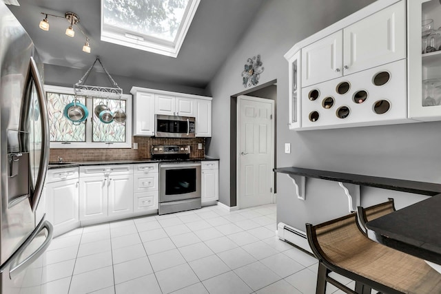 117 E Madison St, East Islip, NY 11730 - kitchen featuring appliances with stainless steel finishes, a skylight, dark countertops, tasteful backsplash, and white cabinets