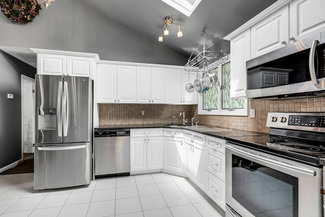 117 E Madison St, East Islip, NY 11730 - kitchen featuring stainless steel appliances, backsplash, vaulted ceiling, white cabinetry, and light tile patterned flooring
