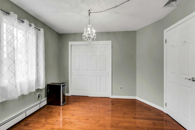 117 E Madison St, East Islip, NY 11730 - unfurnished bedroom with baseboard heating, a chandelier, and wood finished floors