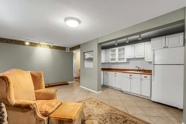 117 E Madison St, East Islip, NY 11730 - kitchen featuring freestanding refrigerator, rail lighting, white cabinets, light tile patterned floors, and glass insert cabinets