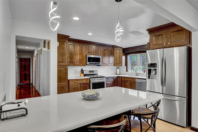 18 Pashen Pl, Dix Hills, NY 11746 - kitchen with stainless steel appliances, light countertops, decorative light fixtures, recessed lighting, and a breakfast bar area