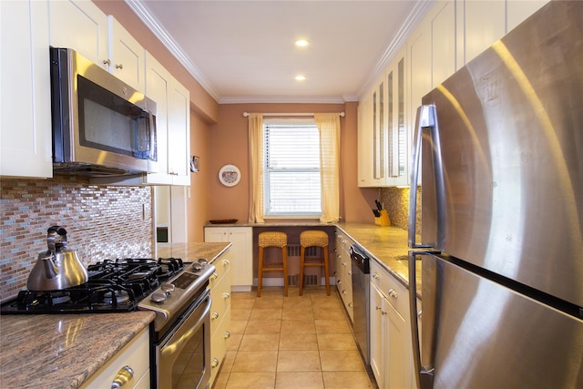 162-41 Powells Cove Blvd Unit 4K, Beechhurst, NY 11357 - kitchen with stainless steel appliances, backsplash, light tile patterned floors, white cabinets, and crown molding