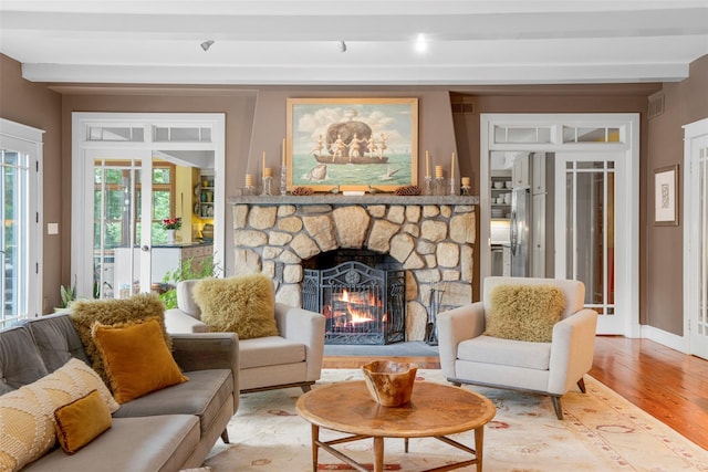 17 Half Moon Rdg, Cold Spring, NY 10516 - living room with a stone fireplace, light wood finished floors, beam ceiling, and french doors