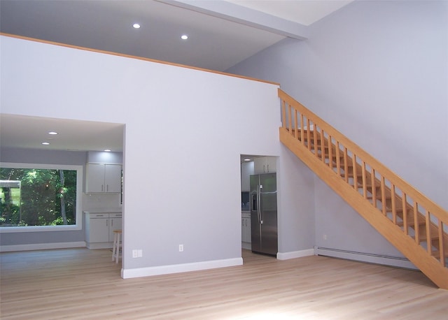121 Lower Sheep Pasture Rd, East Setauket, NY 11733 - unfurnished living room featuring a baseboard heating unit, wood finished floors, stairs, recessed lighting, and a high ceiling