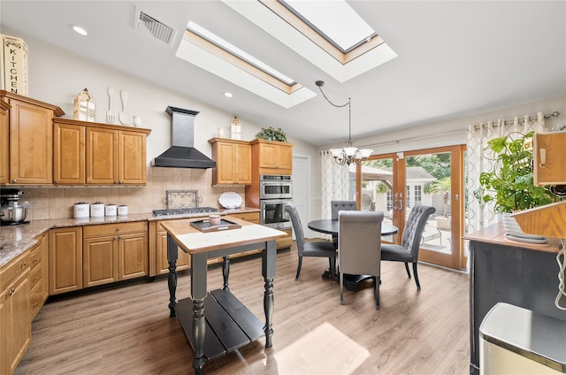 506 Kime Ave, West Islip, NY 11795 - kitchen with wall chimney range hood, a skylight, vaulted ceiling, decorative backsplash, and light wood-style floors