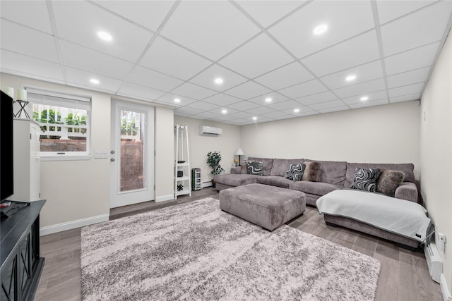 506 Kime Ave, West Islip, NY 11795 - living room featuring an AC wall unit, wood finished floors, recessed lighting, baseboard heating, and a paneled ceiling